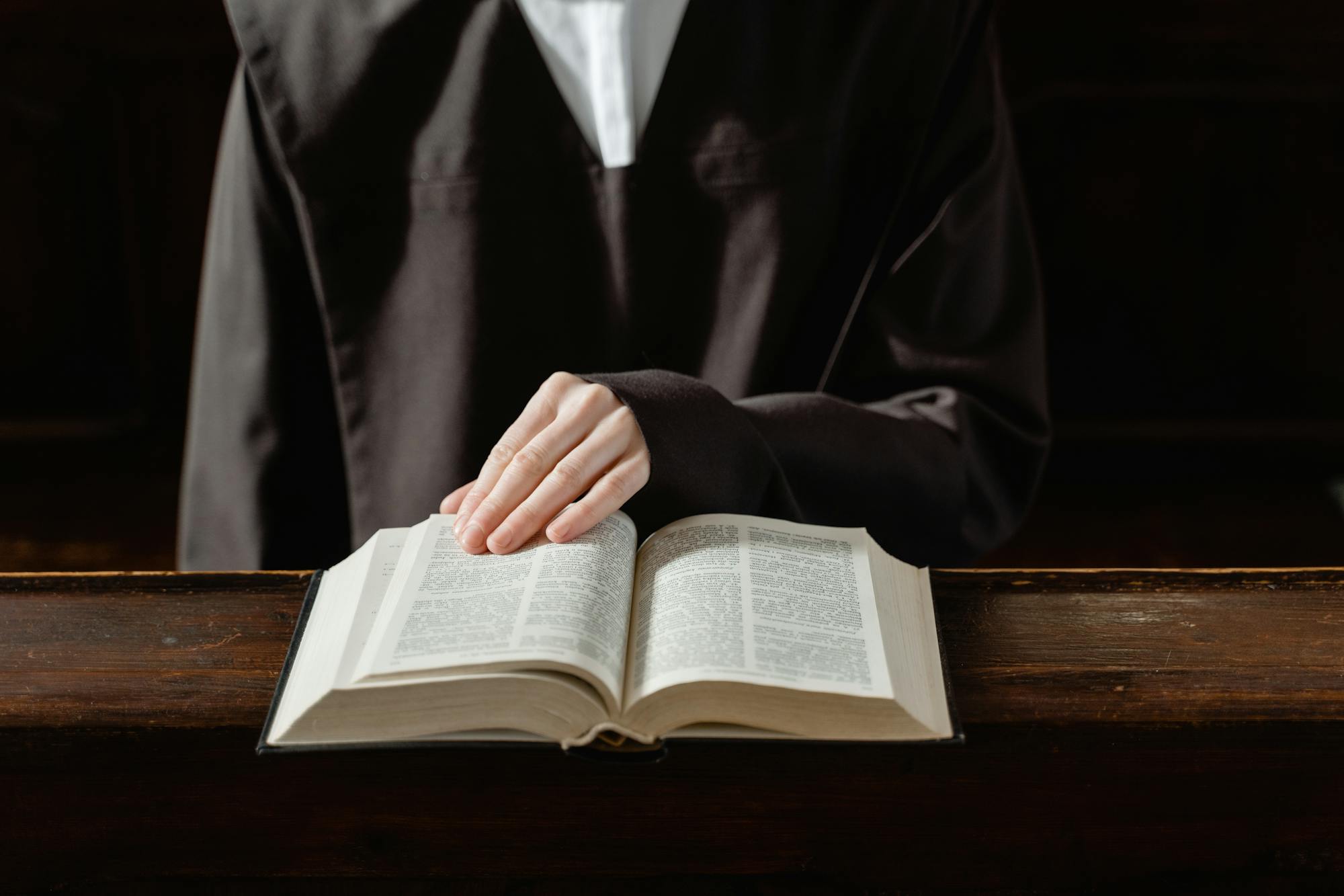 A person in religious attire reading an open Bible, highlighting the connection to spirituality.